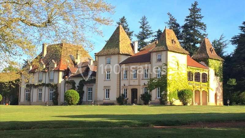 Manoir ancien avec façades en pierre, toits en tuiles et tours, entouré d'un parc verdoyant et d'arbres.