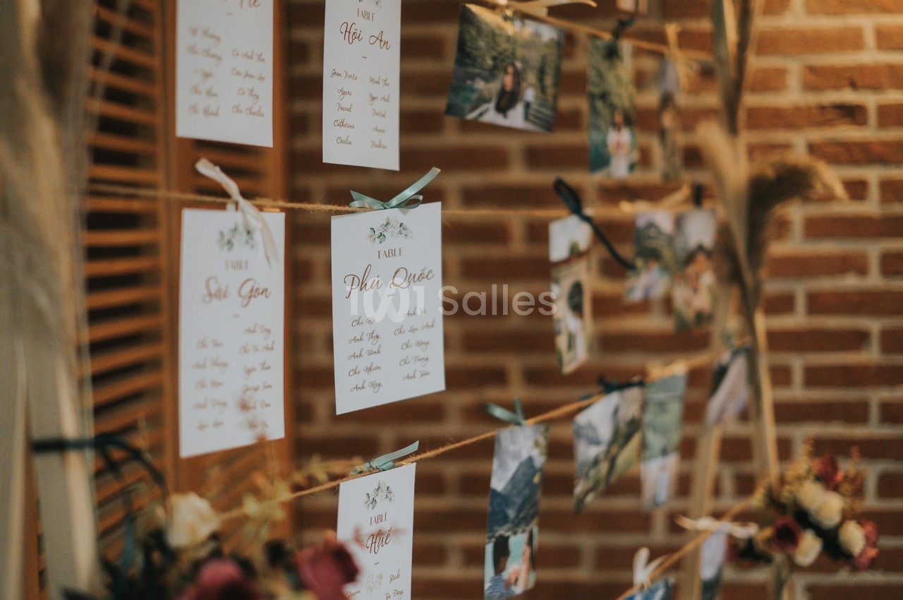 Cartes et photos suspendues sur des cordes, accrochées à des pinces en bois, devant un mur de briques.