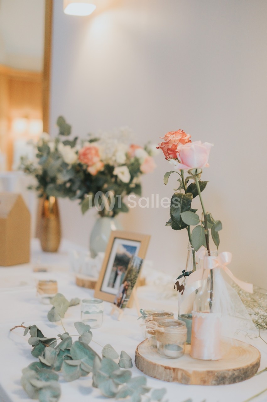 Décoration de table avec roses, eucalyptus, bougies et cadre photo, dans une ambiance lumineuse et élégante.