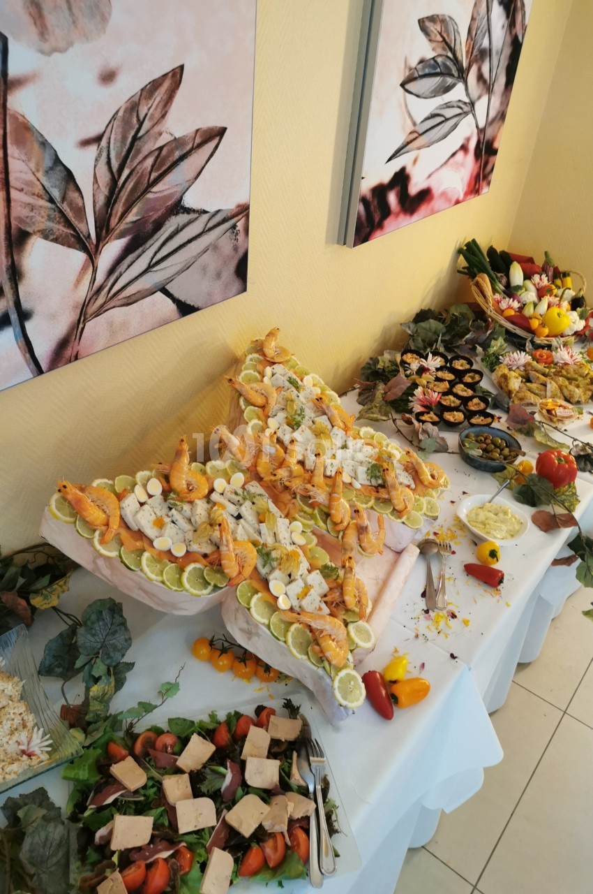 Buffet décoratif avec fruits de mer, légumes, et plats variés disposés sur une table ornée de feuilles et fleurs.