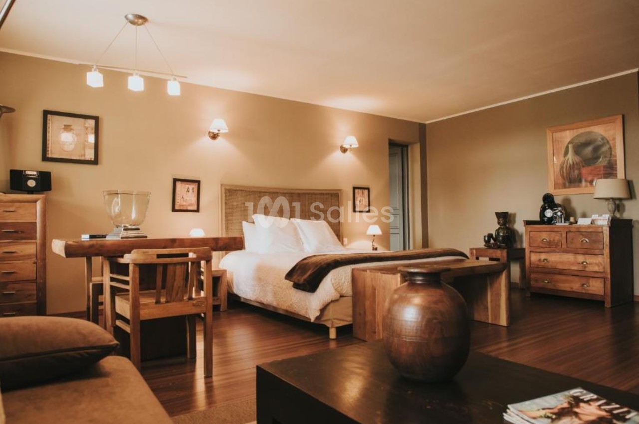Chambre chaleureuse avec lit double, mobilier en bois, éclairage doux et décoration murale.
