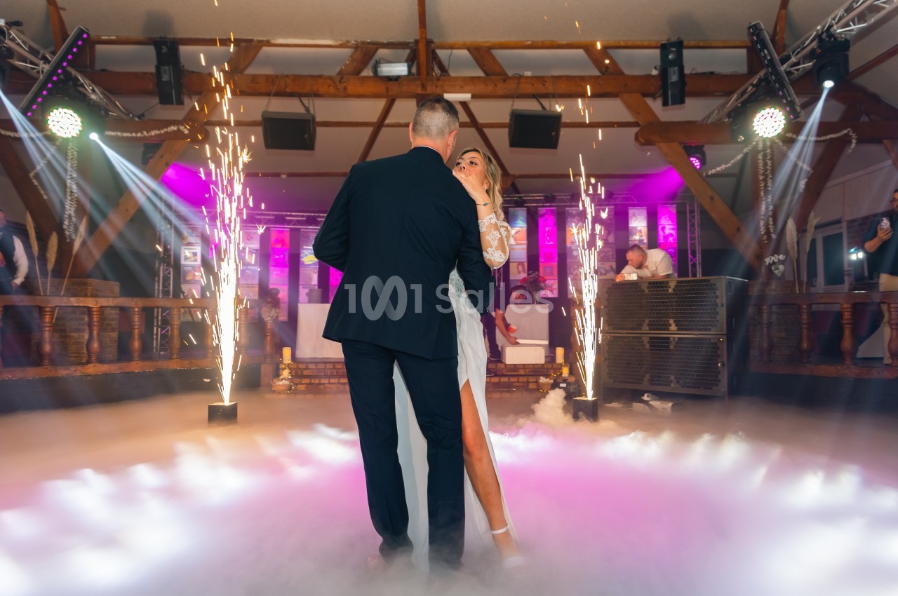 Un couple danse au milieu d'une piste entourée d'effets lumineux et de jets d'étincelles.