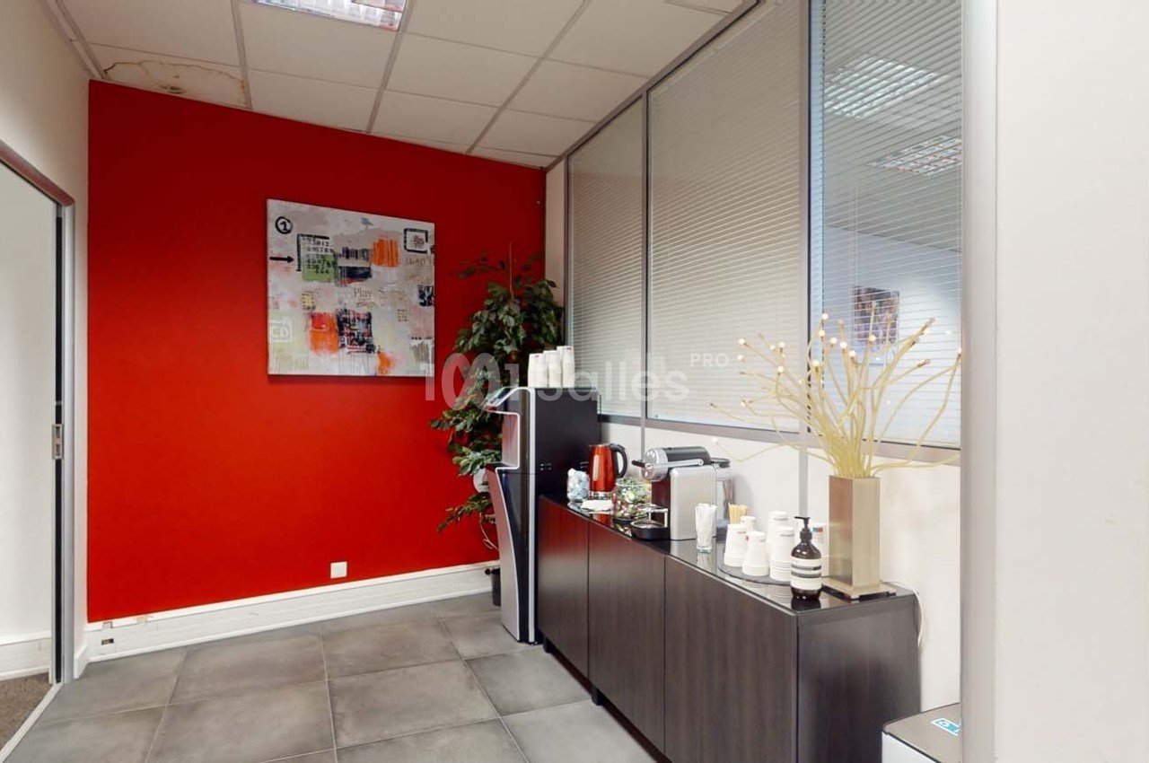 Coin café dans un bureau avec mur rouge, machine à café, étagère avec tasses et plantes décoratives.