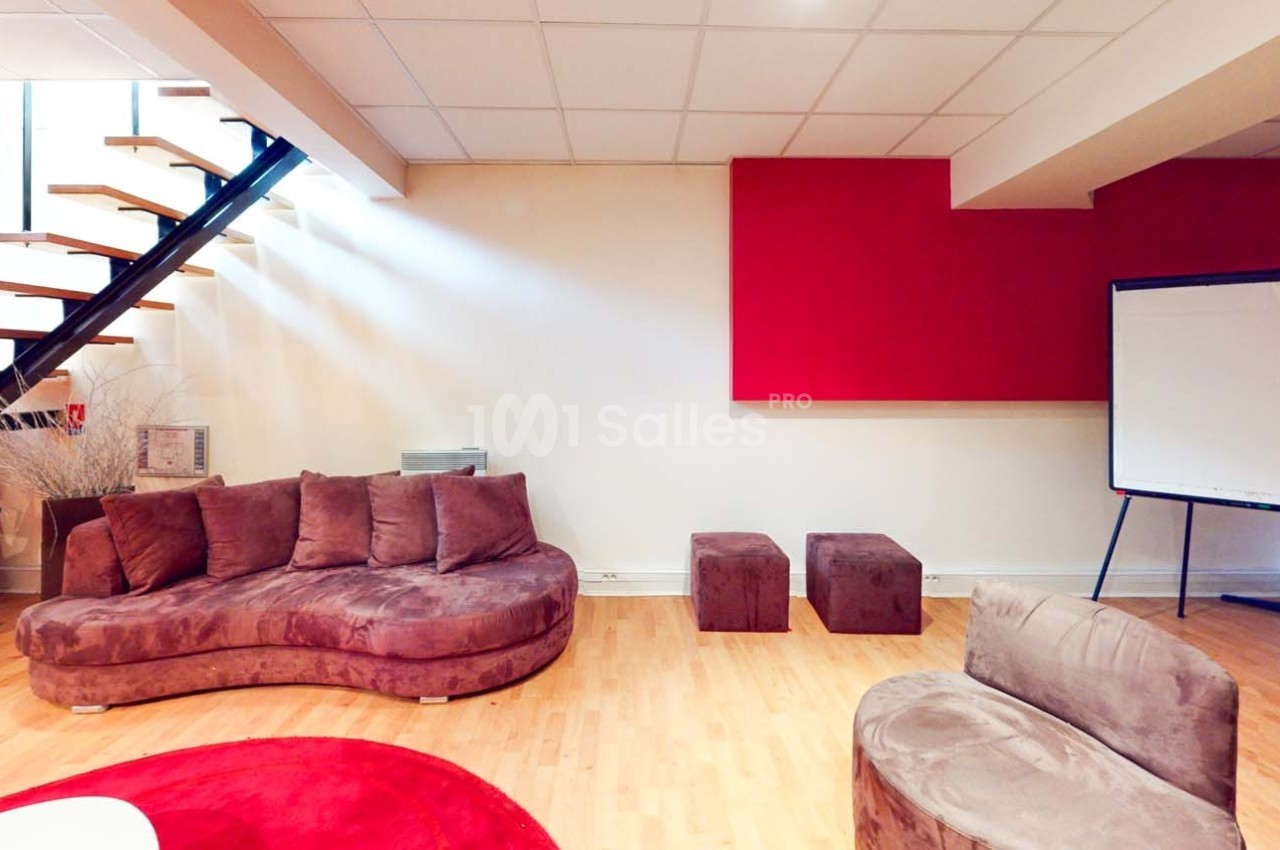 Espace intérieur avec canapé en velours marron, escalier moderne, tableau blanc et décoration minimaliste.