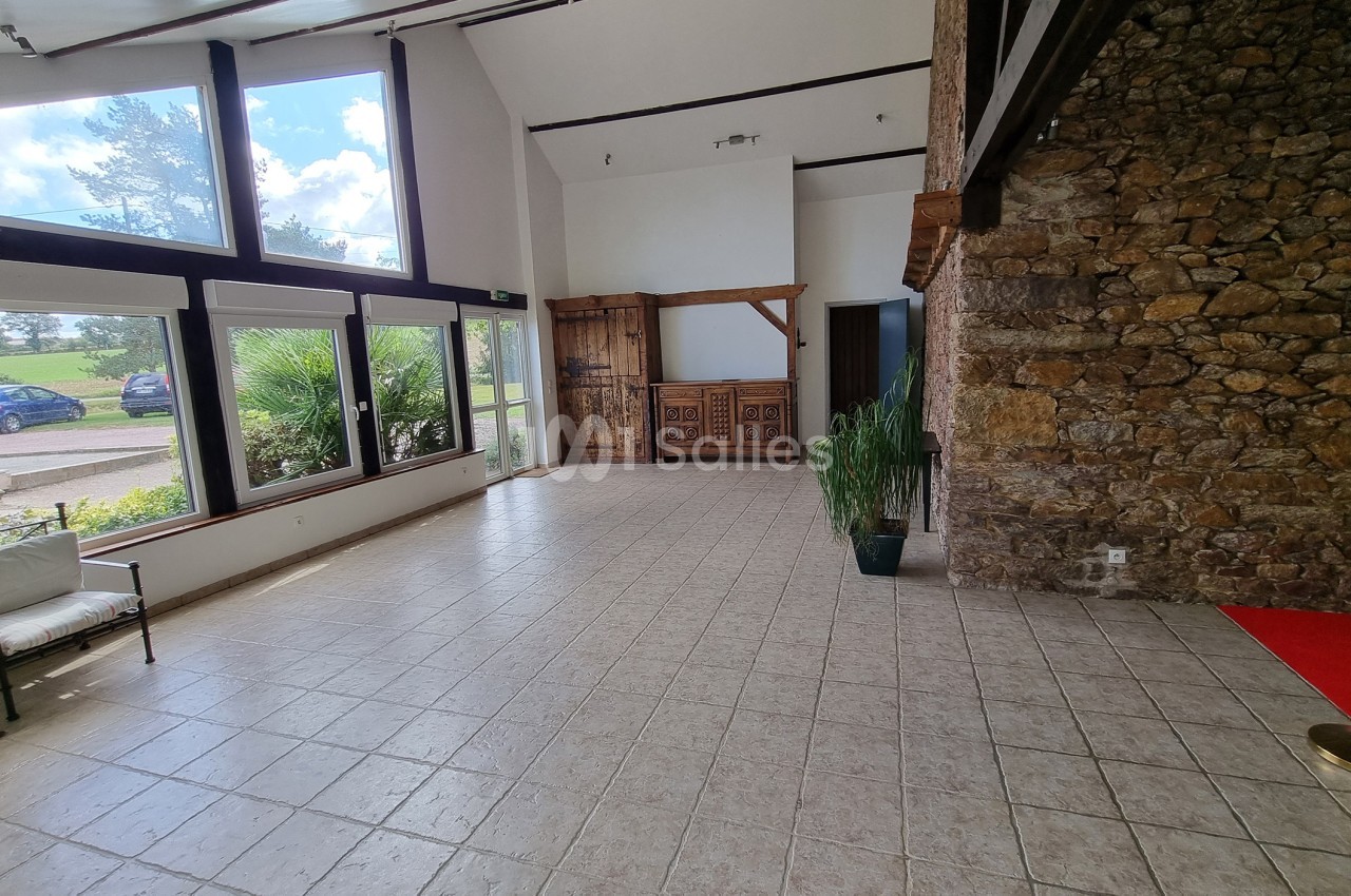 Salle lumineuse avec grandes baies vitrées, murs en pierre, carrelage clair et mobilier minimaliste.