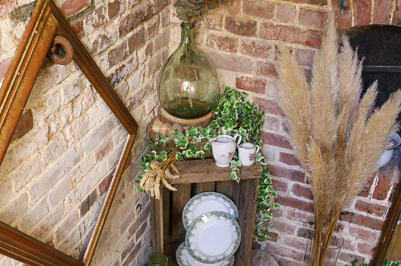 Décoration rustique avec cadres en bois, vaisselle ancienne, carafe en verre, lierre et herbes séchées sur fond de mur en…