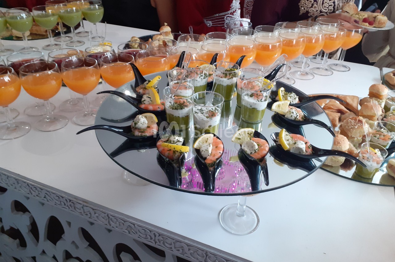 Plateau de verrines et amuse-bouches variés disposés sur une table lors d'un buffet.