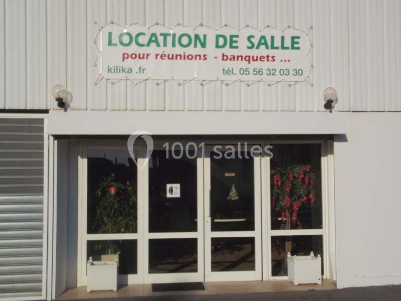 Façade d'un bâtiment avec une entrée vitrée et un panneau indiquant ’Location de salle pour réunions - banquets’.