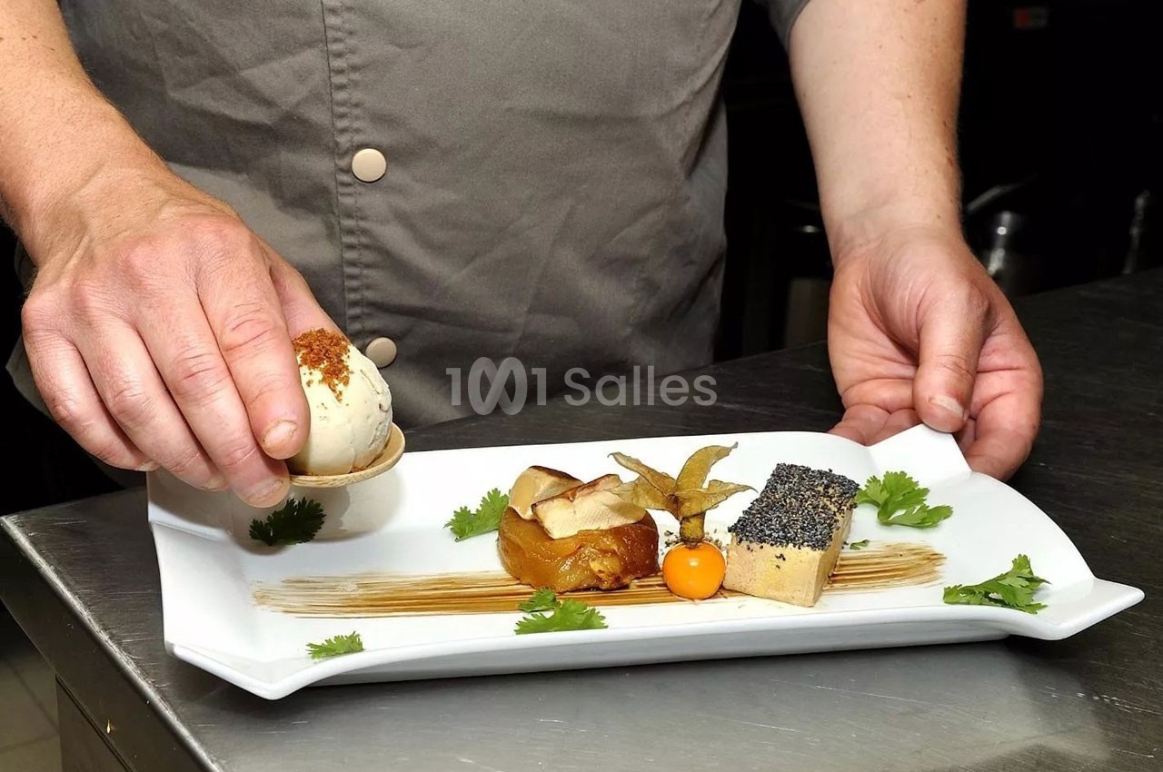 Un chef dispose un œuf garni sur une assiette gastronomique avec foie gras, purée et décoration soignée.