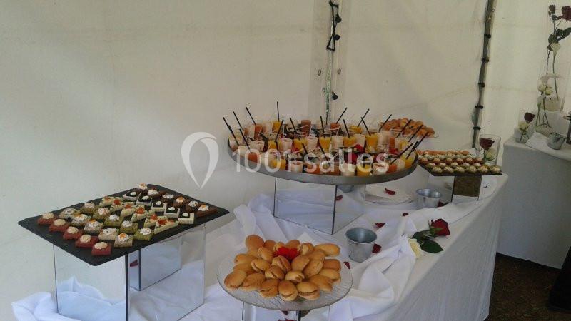 Buffet de desserts variés avec verrines, mignardises et madeleines disposés sur des présentoirs dans une tente blanche.