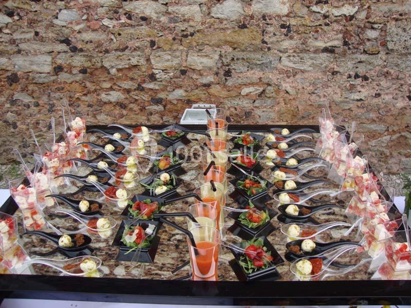 Buffet de verrines et amuse-bouches variés disposés sur une table devant un mur en pierre.
