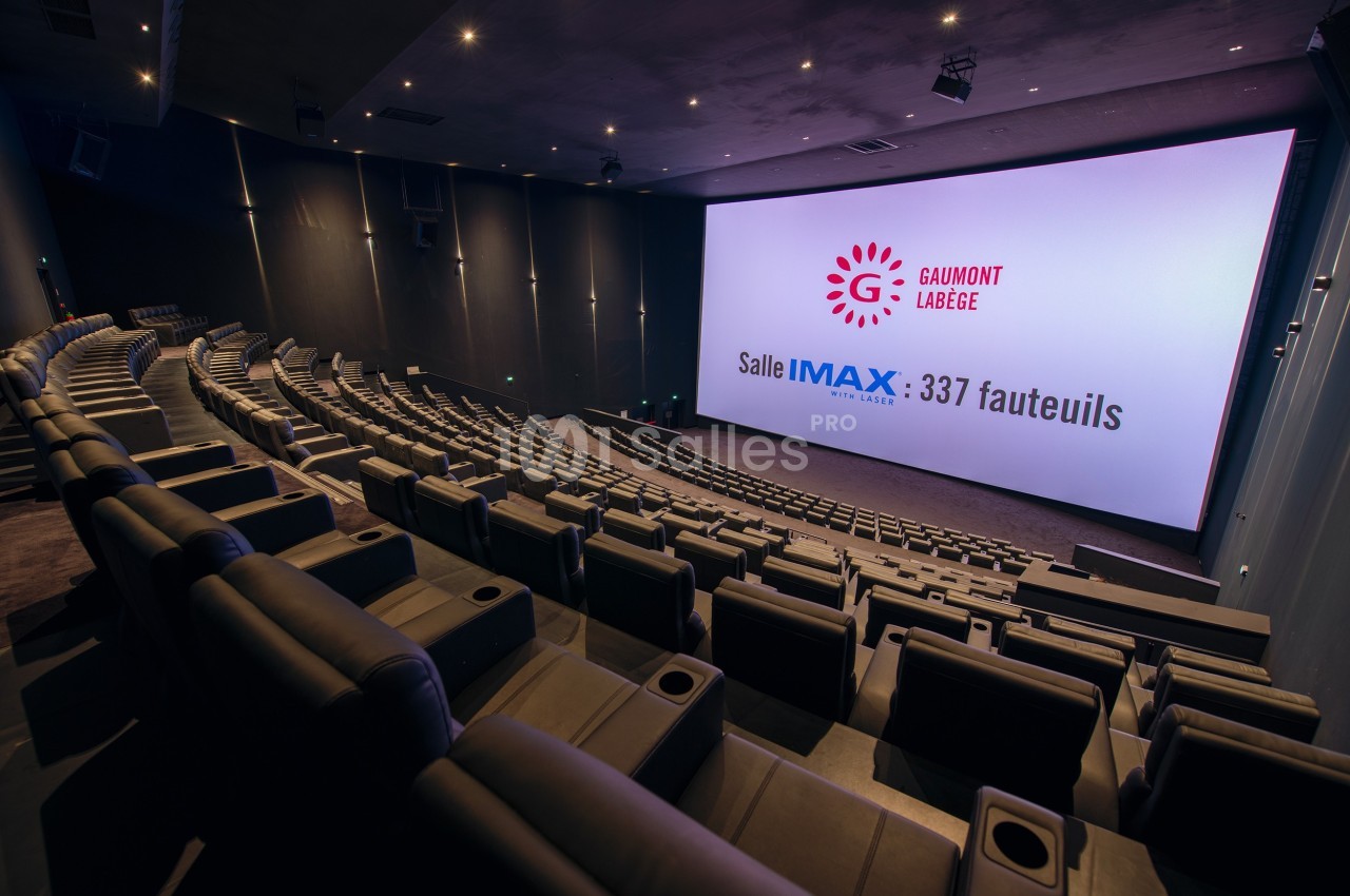 Salle de cinéma IMAX vide avec 337 fauteuils, écran géant et éclairage tamisé.