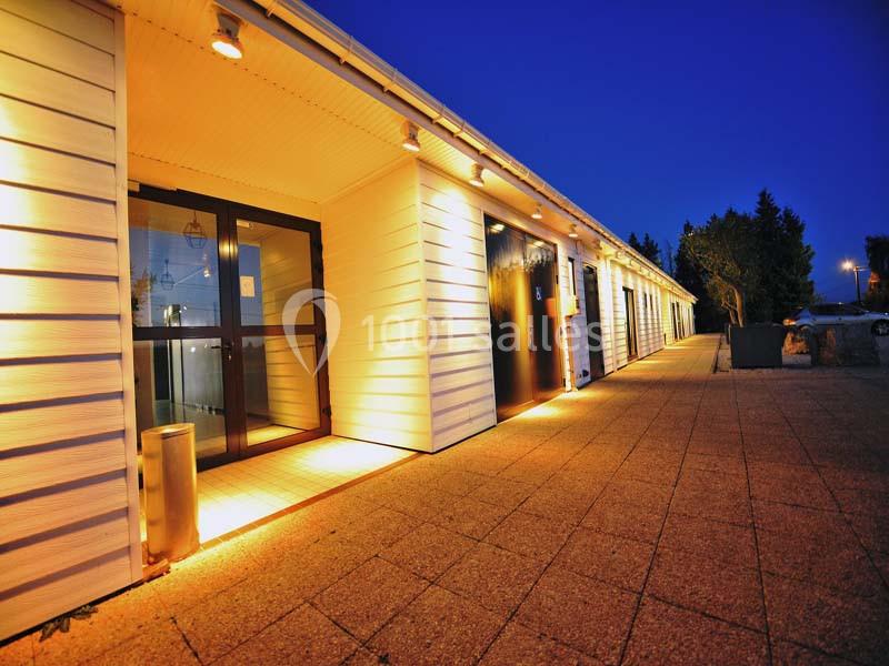 Façade d'un bâtiment moderne avec éclairage extérieur au crépuscule, vue sur une allée pavée.