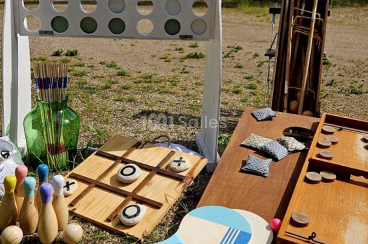 Jeux d'extérieur en bois, dont un morpion, des quilles, un jeu de palets et un jeu de lancer, disposés sur un sol…