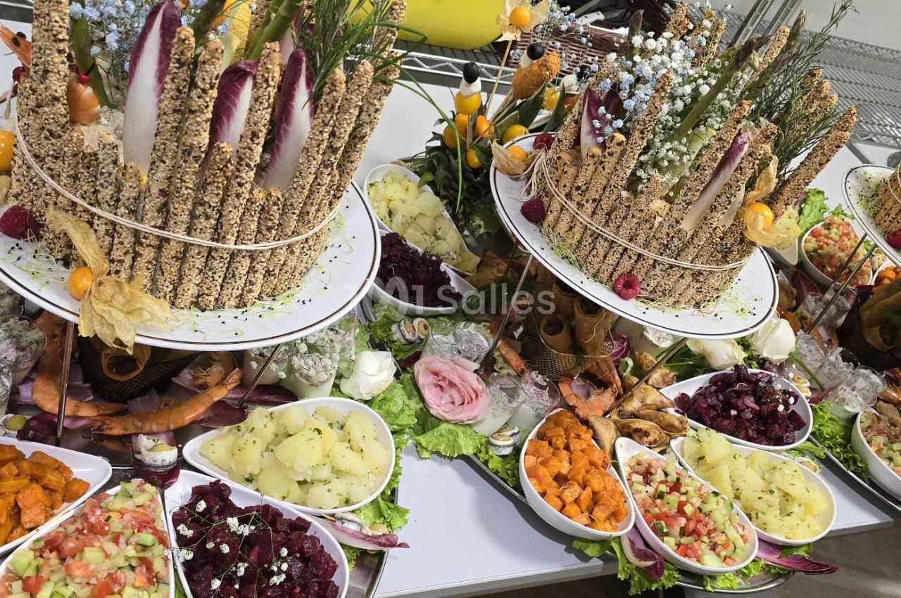 Plateaux garnis de légumes frais, salades colorées, fleurs comestibles et décorations végétales sur une table.
