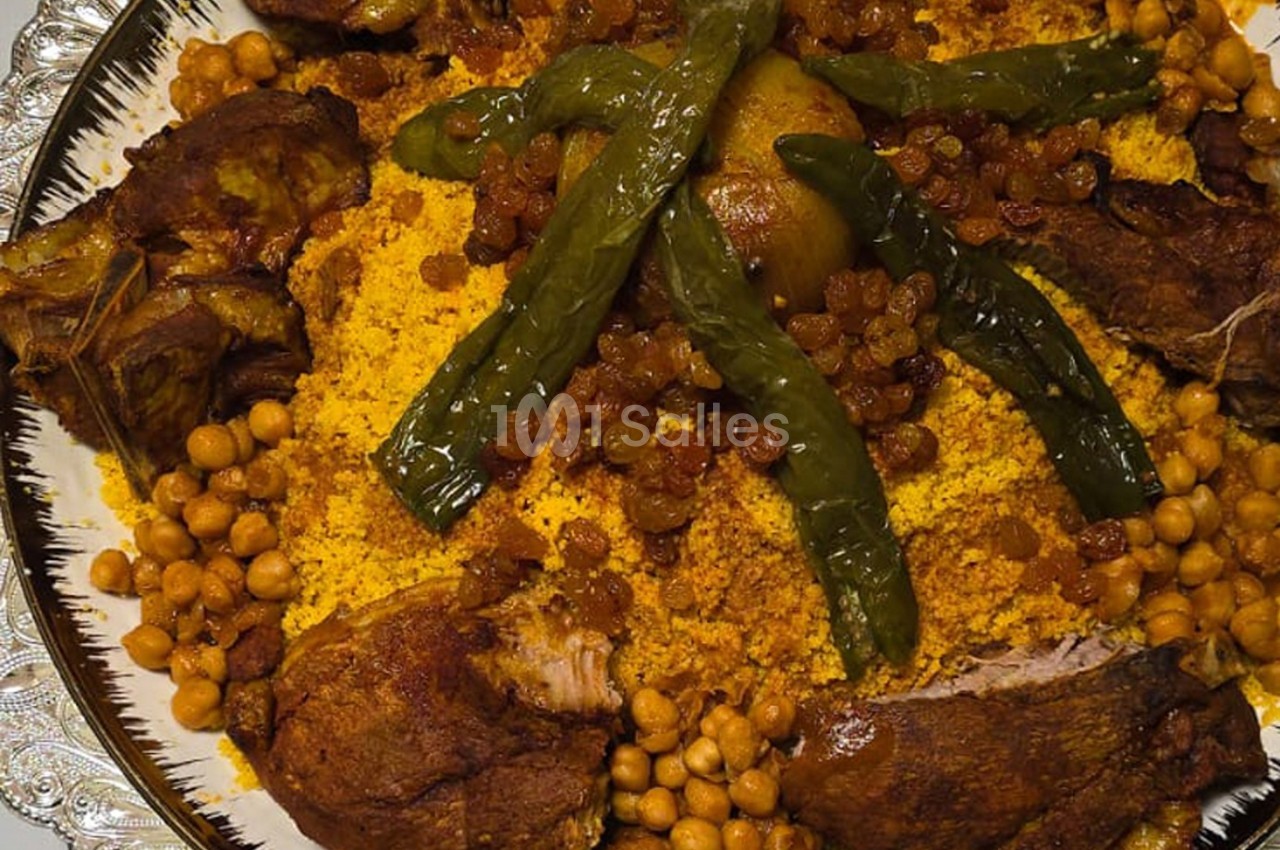 Plat de couscous garni de légumes, pois chiches, raisins secs, morceaux de viande et piments verts.