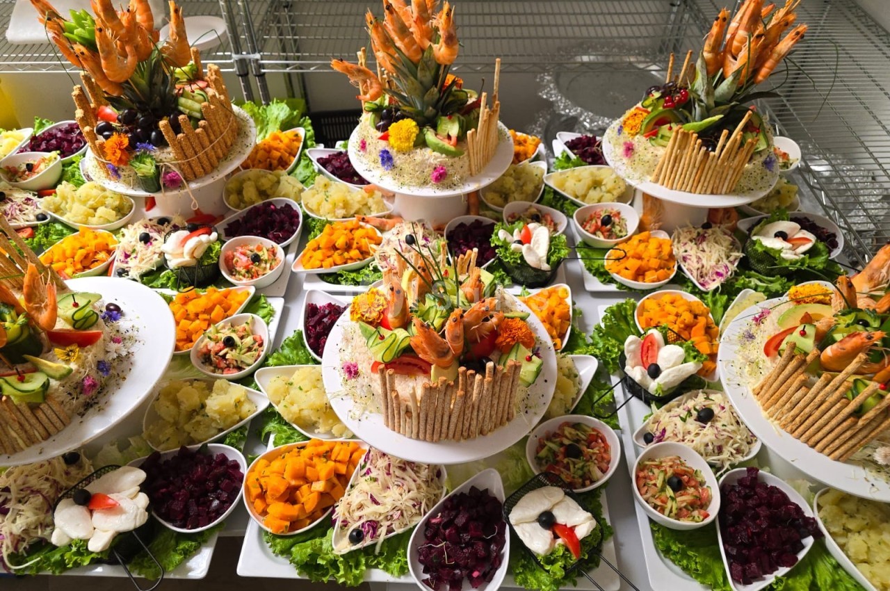Plateau de buffet garni de légumes, fruits, crevettes et décorations comestibles, disposé sur plusieurs étages.