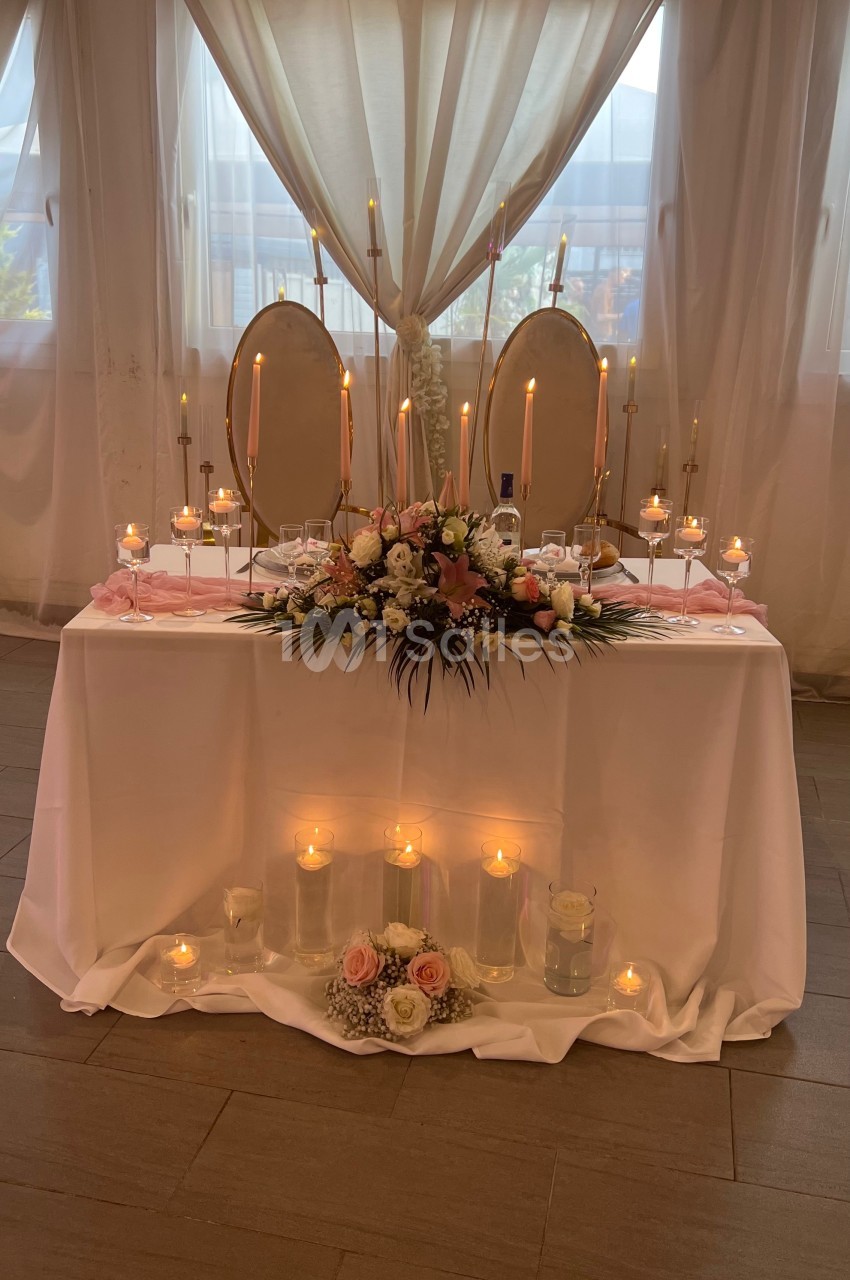 Table décorée pour un mariage avec bougies, fleurs roses et blanches, et deux miroirs ovales en arrière-plan.