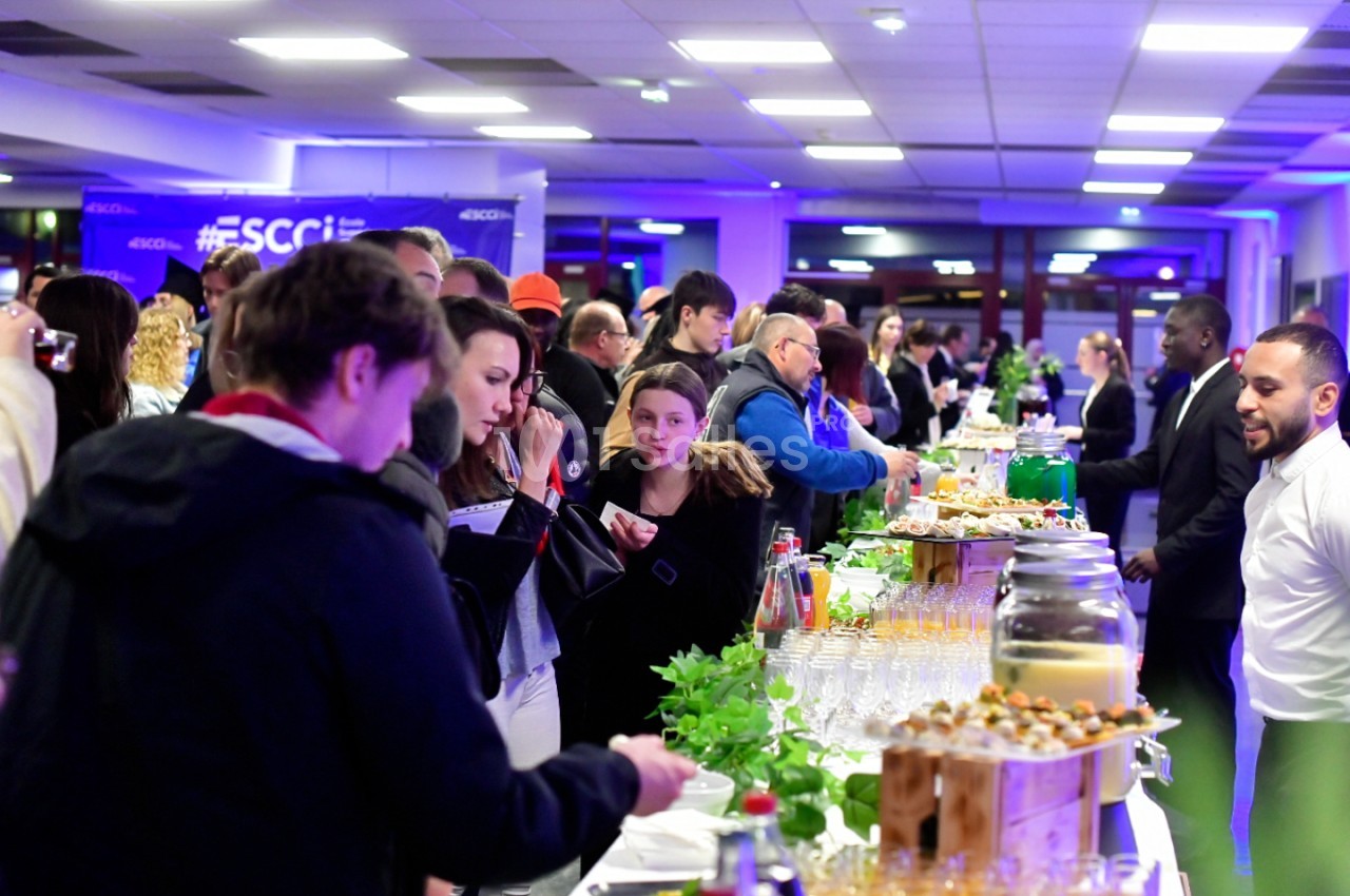 Salle intérieure avec éclairage bleu - convives debout autour de tables dressées avec amuse-bouches et boissons.