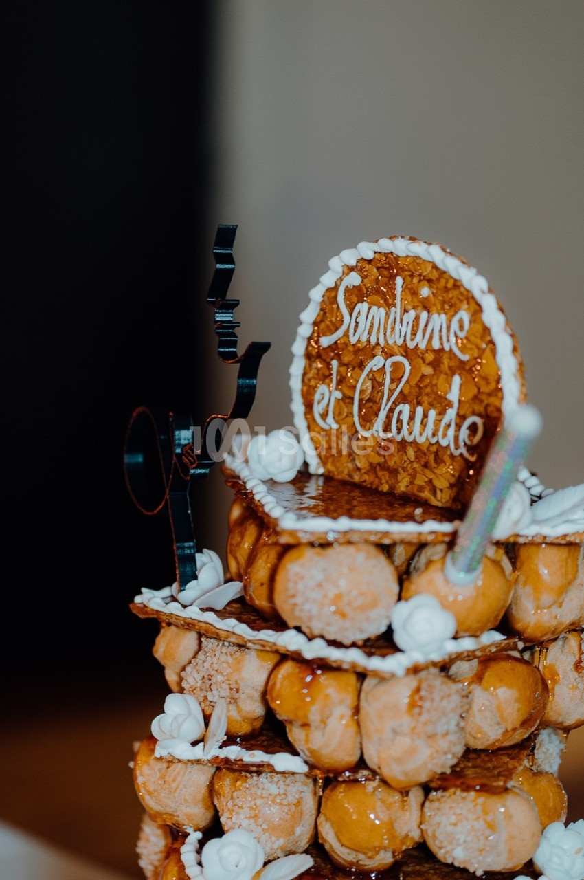 Pièce montée en choux caramélisés décorée de roses en sucre et d'un disque portant les prénoms ’Sandrine et Claude’.