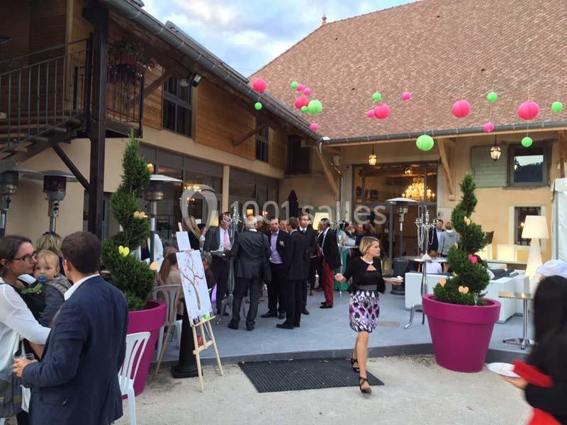 Groupe de personnes réunies dans une cour extérieure décorée de lanternes colorées, près d'un bâtiment en bois.