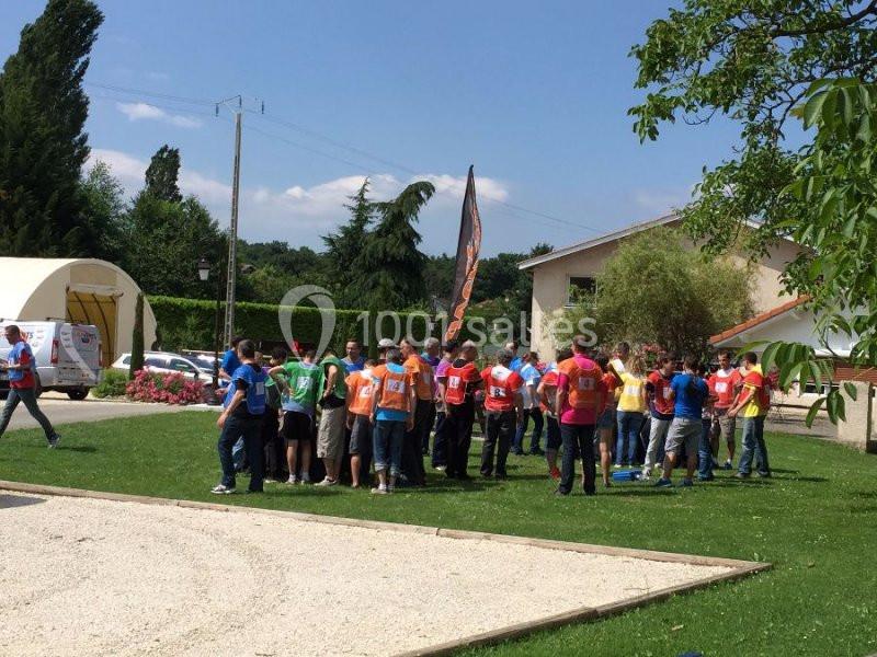 Un groupe de personnes en gilets colorés participe à une activité en plein air sur une pelouse près de bâtiments.