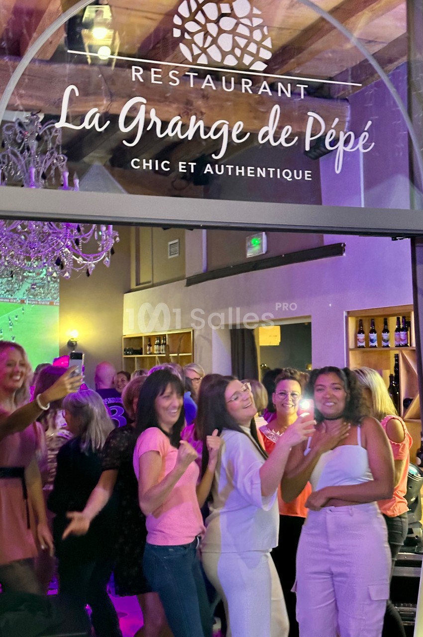 Des personnes souriantes dansent et s'amusent à l'intérieur d'un restaurant sous une enseigne lumineuse.