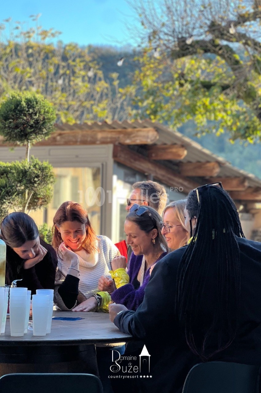 Un groupe de personnes assises autour d'une table en extérieur, discutant et partageant un moment convivial.