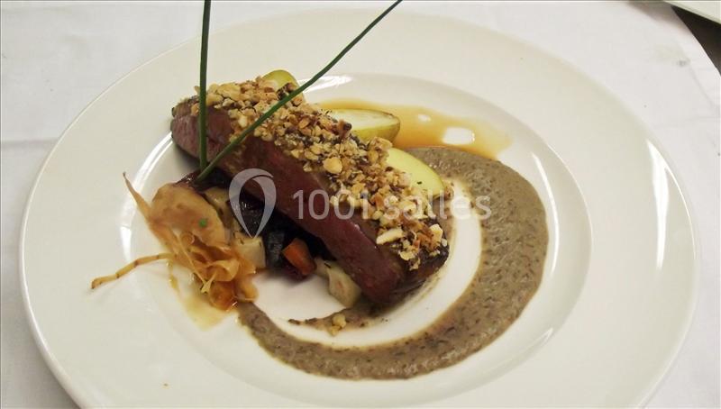 Plat gastronomique composé d'une viande garnie de noix, accompagné de légumes, d'une sauce crémeuse et d'une décoration…