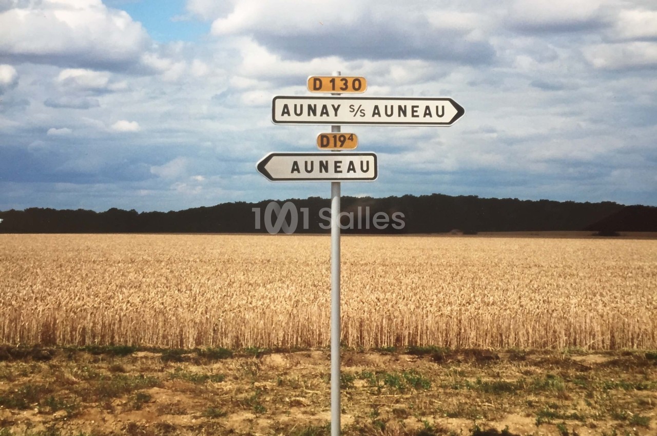 Panneau de signalisation indiquant les directions vers Aunay-sous-Auneau et Auneau, devant un champ de blé sous un ciel…