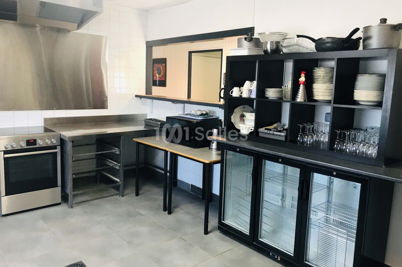 Cuisine équipée avec four, plaques de cuisson, étagères de rangement, vaisselle, micro-ondes et réfrigérateurs vitrés.
