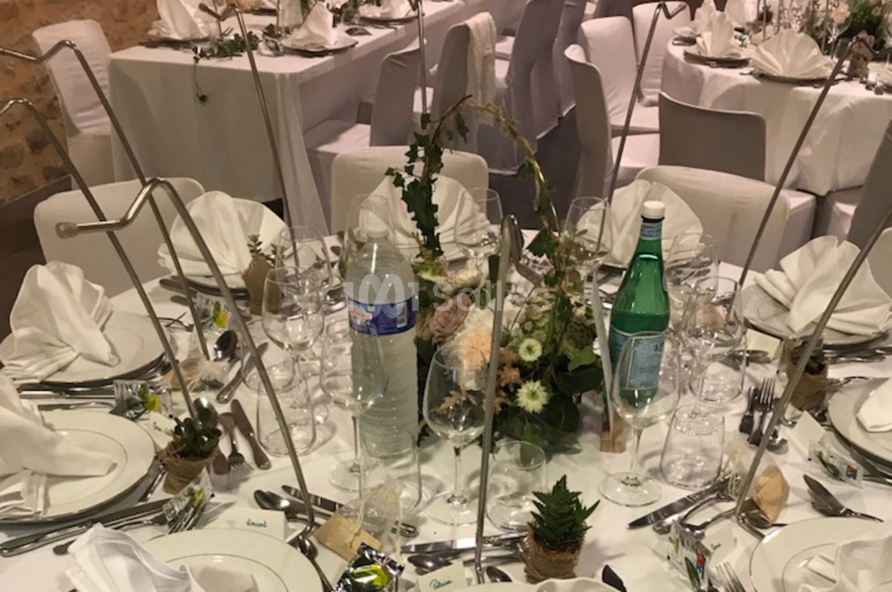 Table de réception élégamment dressée avec nappes blanches, vaisselle, serviettes pliées et décoration florale.