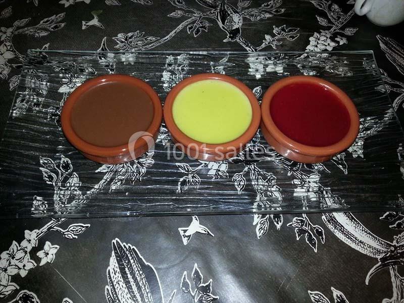 Trois ramequins en terre cuite contenant des crèmes dessert au chocolat, à la vanille et aux fruits rouges, sur un plateau…