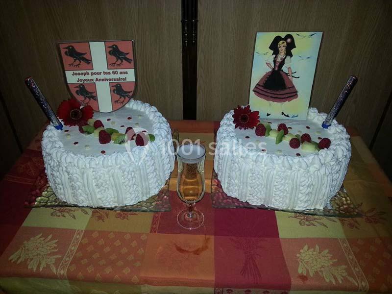 Deux gâteaux décorés de fruits rouges et de fleurs, avec des illustrations et une flûte de champagne entre eux.