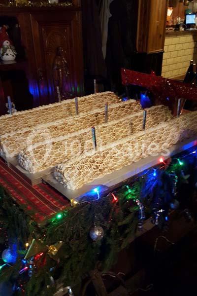 Grandes bûches pâtissières décorées de glaçage blanc, présentées sur une table ornée de guirlandes lumineuses et de…