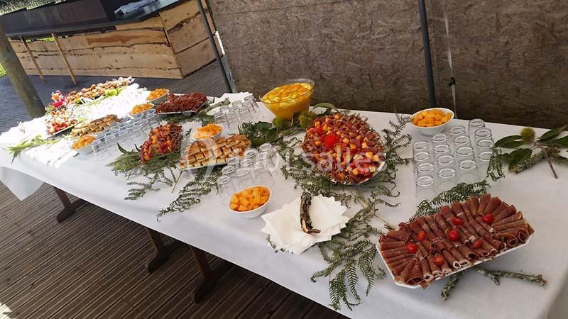 Buffet dressé sur une table avec charcuterie, fruits, verrines et décorations végétales.