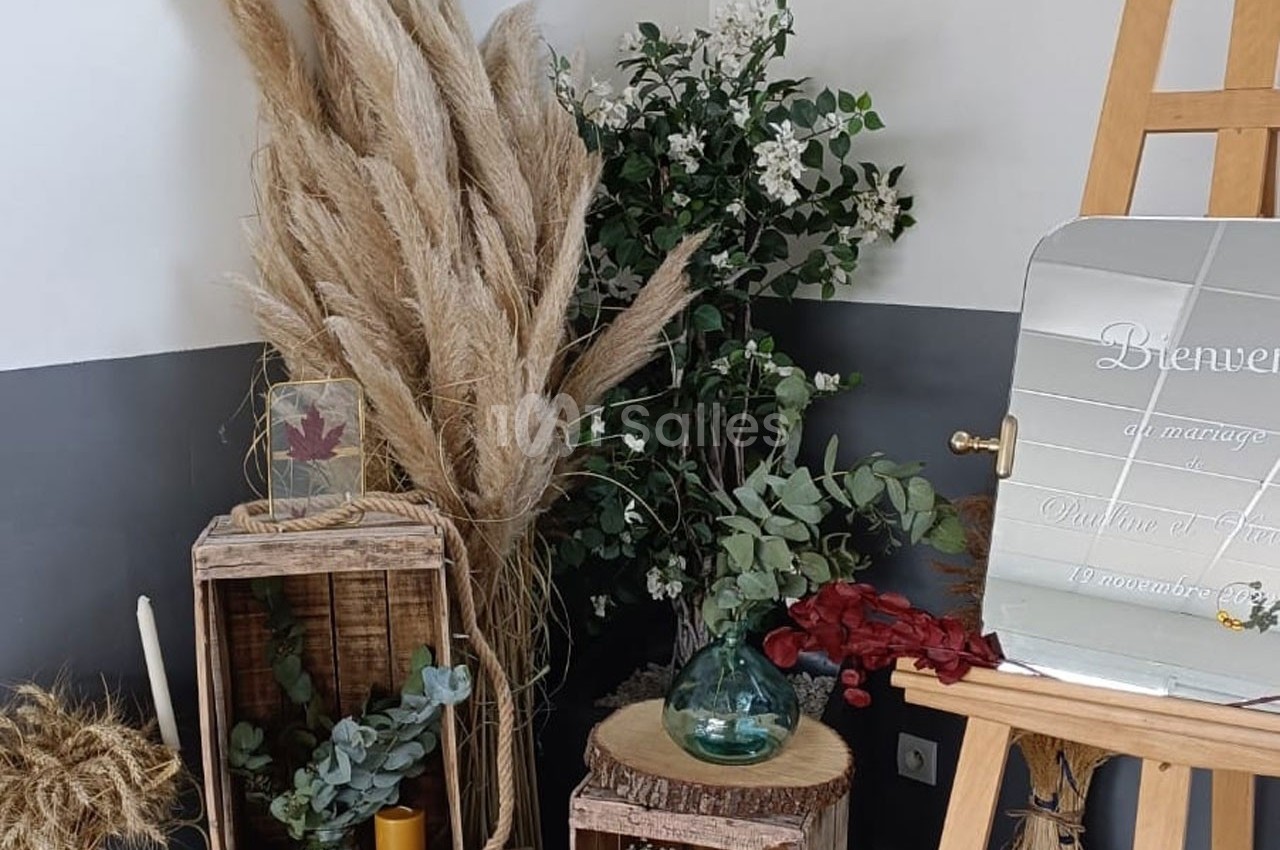 Décoration florale avec herbes de la pampa, feuillage, bougies et miroir sur chevalet dans un coin de pièce.