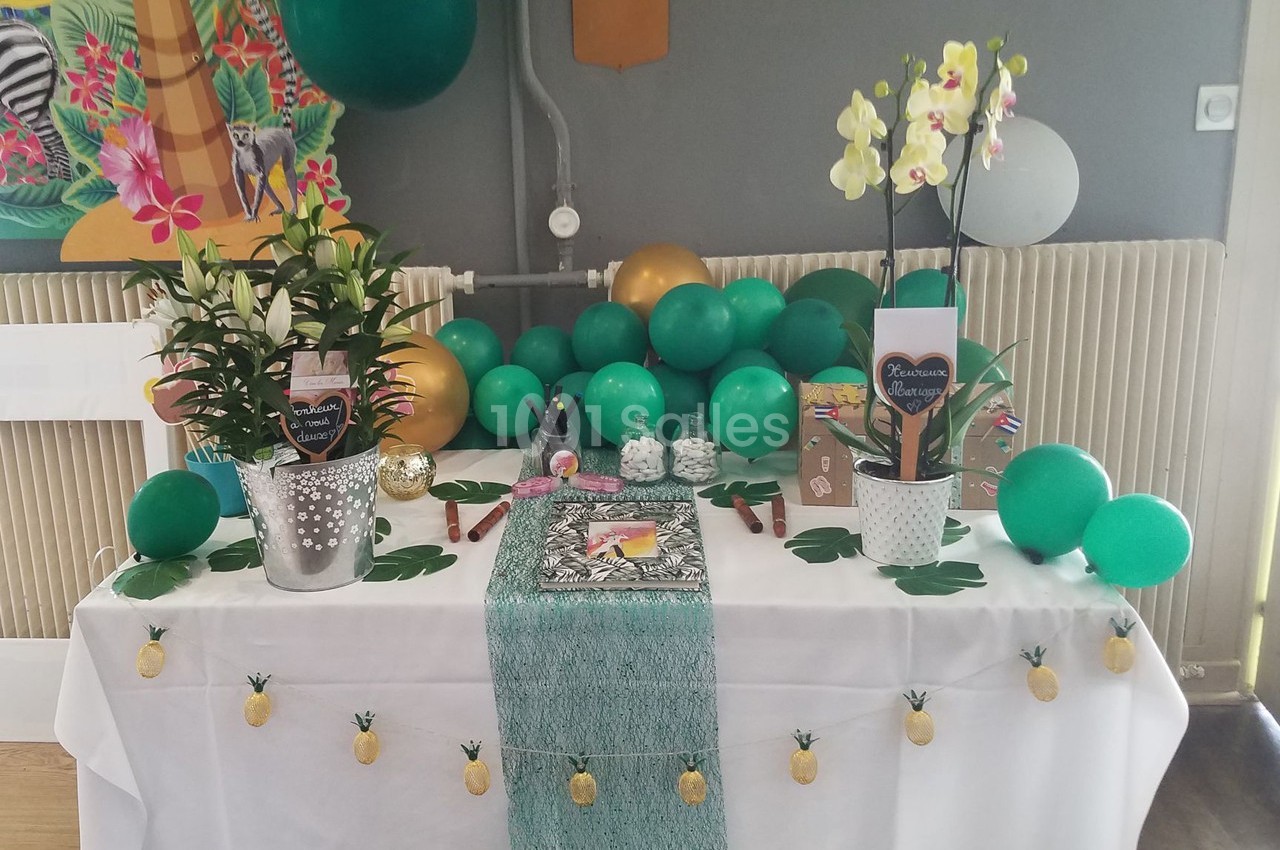 Table décorée avec des ballons verts, des plantes en pot, des orchidées et des accessoires sur le thème tropical.