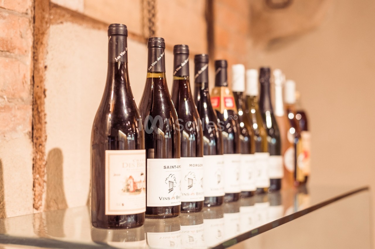 Bouteilles de vin alignées sur une étagère en verre devant un mur en briques.