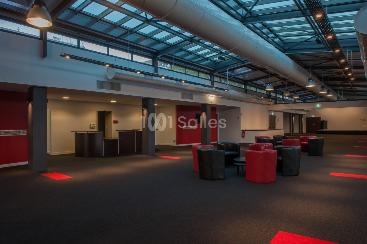 Espace intérieur moderne avec plafond vitré, mobilier rouge et noir, et éclairage tamisé.