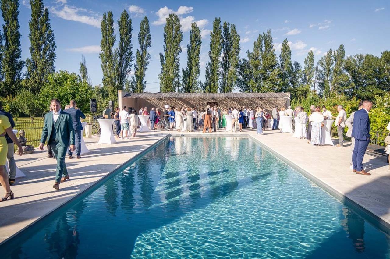 Groupe de personnes rassemblées autour d'une piscine extérieure lors d'un événement en plein air par temps ensoleillé.