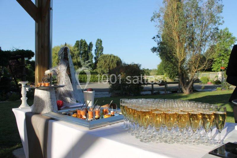 Table dressée en extérieur avec des coupes de champagne et des amuse-bouches, entourée de verdure.
