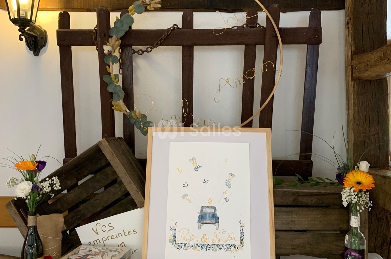 Illustration d'une voiture entourée de papillons, encadrée et posée sur une table décorée de fleurs et d'éléments rustiques.