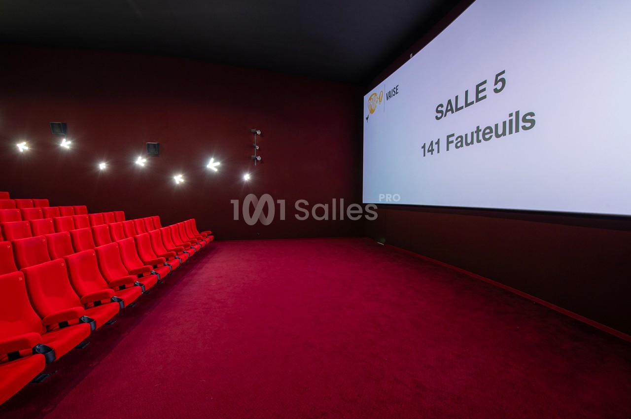 Salle de cinéma vide avec des sièges rouges, écran affichant ’Salle 5, 141 Fauteuils’, éclairage mural discret.