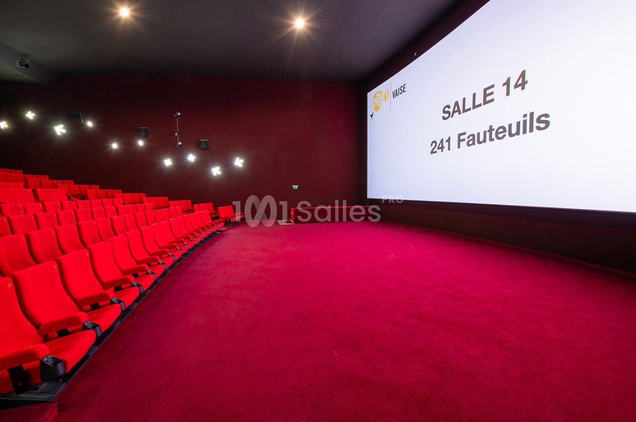 Salle de cinéma avec des sièges rouges, un écran géant affichant ’Salle 14, 241 fauteuils’ et un éclairage tamisé.