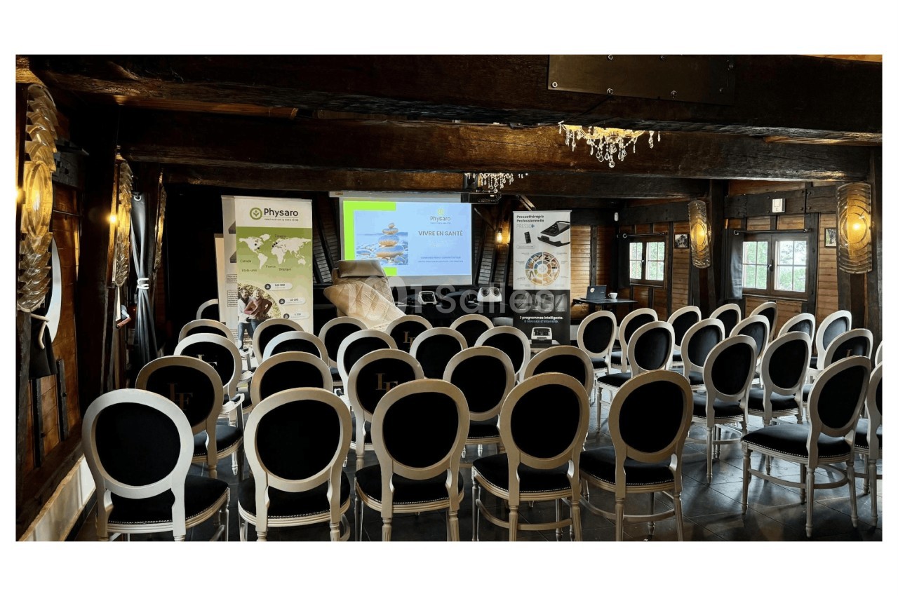 Salle de conférence avec des chaises alignées face à un écran de projection et des affiches promotionnelles.