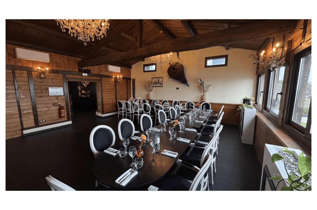 Salle de réception avec tables dressées, chaises noires et blanches, décor en bois et lustres suspendus.