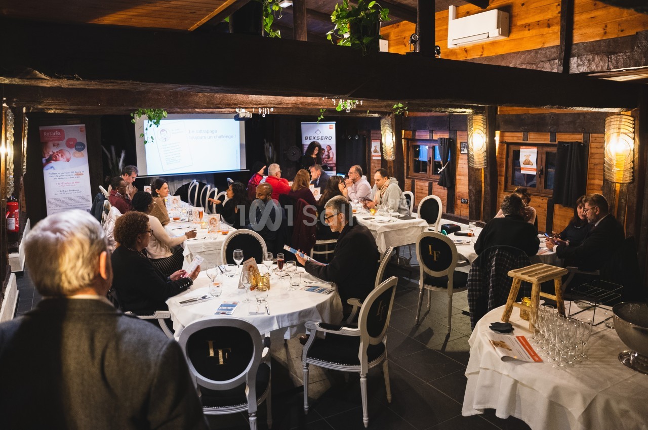 Des personnes assises autour de tables dans une salle en bois lors d'une réunion ou d'un événement professionnel.