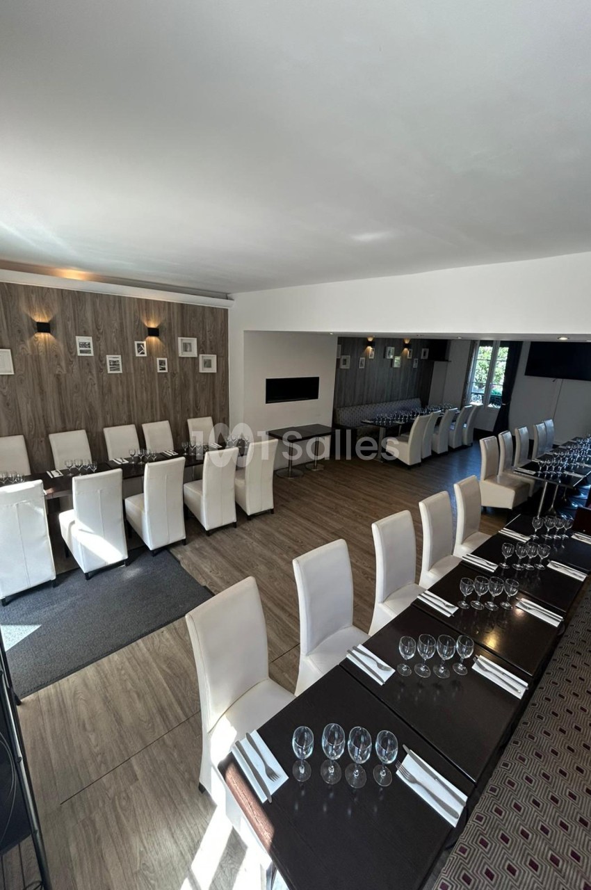 Salle de restaurant lumineuse avec tables dressées, chaises blanches et décoration murale sobre.