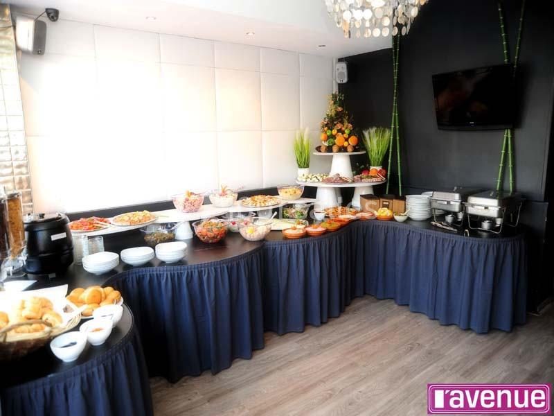 Buffet varié avec plats chauds, salades, pains et fruits, disposé dans une salle élégante avec décoration moderne.